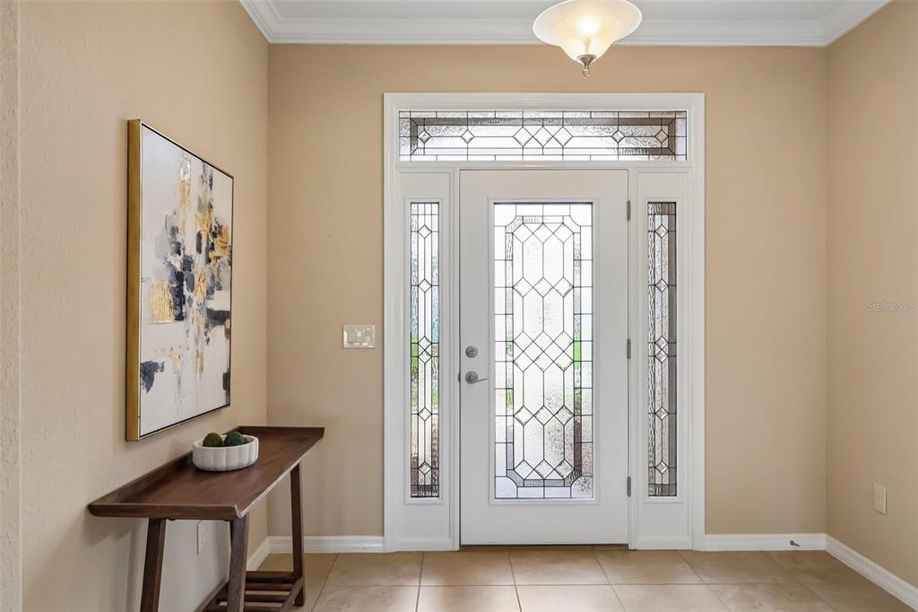 An entryway features a white front door with glass panels, a console table, and artwork — 27143 ROANOKE DRIVE, LEESBURG, FL