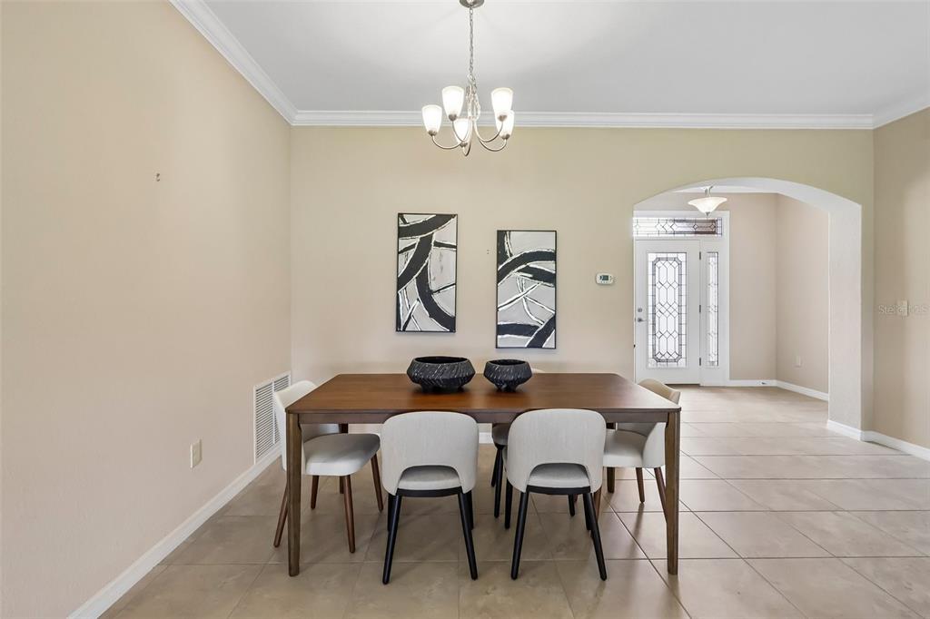 A dining room features a wooden table, four chairs, two wall art pieces, and tile flooring — 27143 ROANOKE DRIVE, LEESBURG, FL