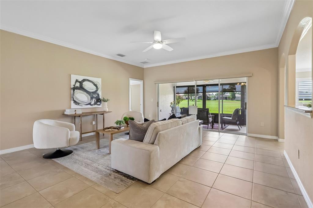 A living room with tile floors, a white sofa, and sliding glass doors to a patio — 27143 ROANOKE DRIVE, LEESBURG, FL
