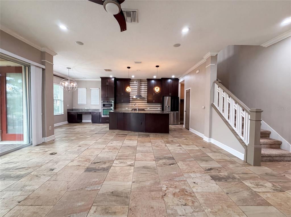 A kitchen with dark cabinetry, a central island, and tile flooring, adjacent to a staircase — 7304 MILESTONE DRIVE, APOLLO BEACH, FL