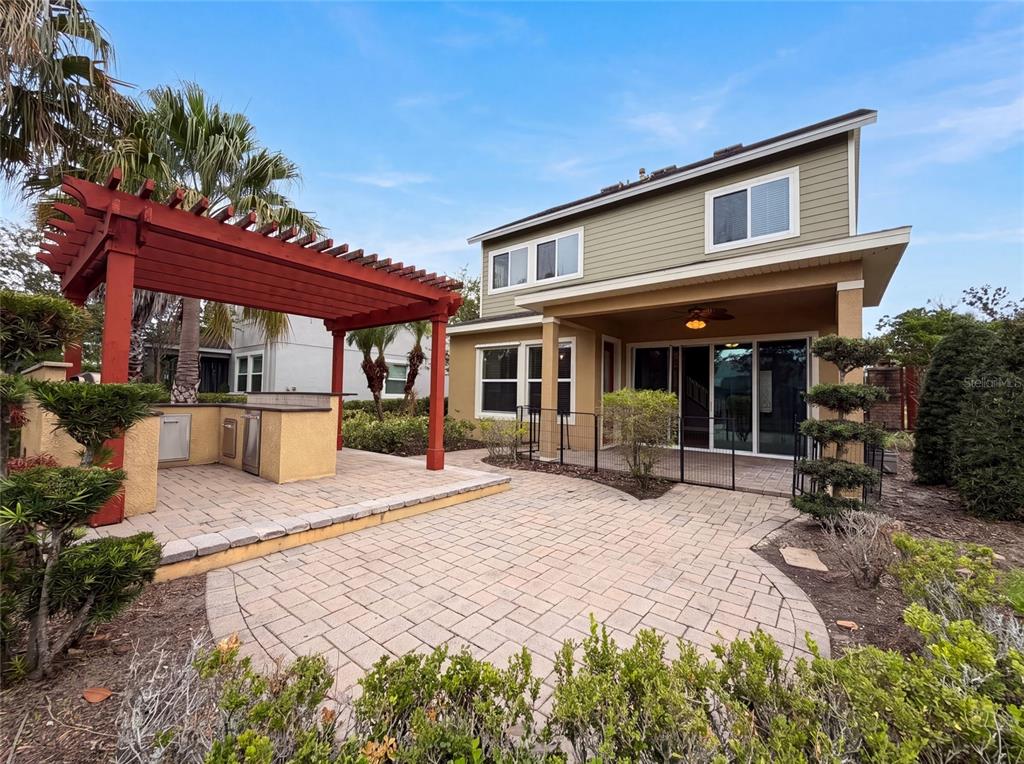 A two-story house with a paved patio, outdoor kitchen, and a red wooden pergola — 7304 MILESTONE DRIVE, APOLLO BEACH, FL
