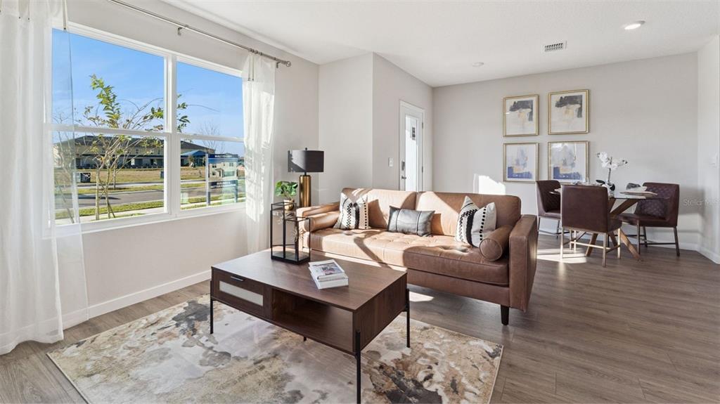 A living room with a brown leather sofa, coffee table, and dining area with wood flooring — 288 PRESTON COVE DRIVE, ST CLOUD, FL