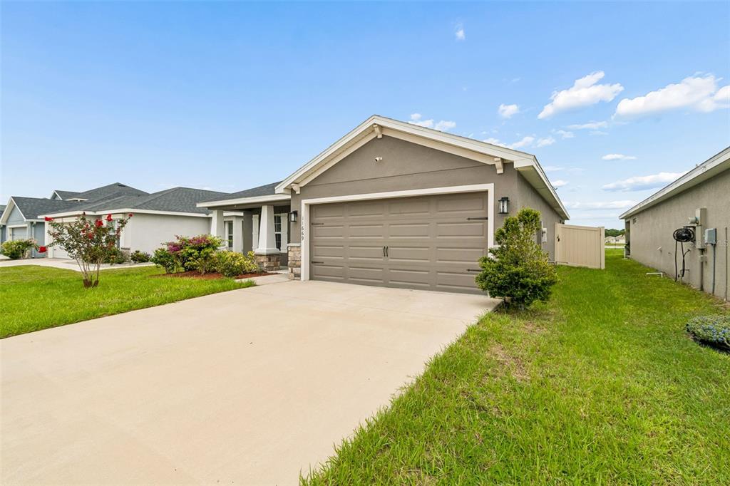 A tan, single-story suburban house features a two-car garage and a concrete driveway — 11669 STONE PINE STREET, RIVERVIEW, FL