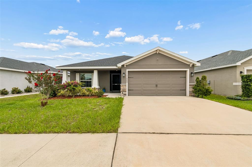 A single-story suburban house with a gray exterior, two-car garage, and a landscaped front yard — 11669 STONE PINE STREET, RIVERVIEW, FL