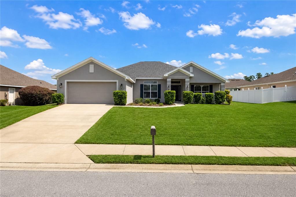 A single-story suburban house with a gray exterior, two-car garage, and a manicured front lawn — 4321 NW 1ST COURT ROAD, OCALA, FL