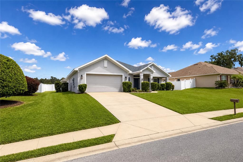 A single-story suburban house with a two-car garage and a green lawn under blue skies — 4321 NW 1ST COURT ROAD, OCALA, FL
