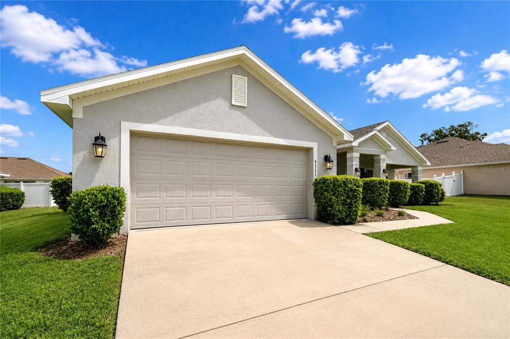 A single-story house with a two-car garage, light gray stucco exterior, and manicured landscaping — 4321 NW 1ST COURT ROAD, OCALA, FL