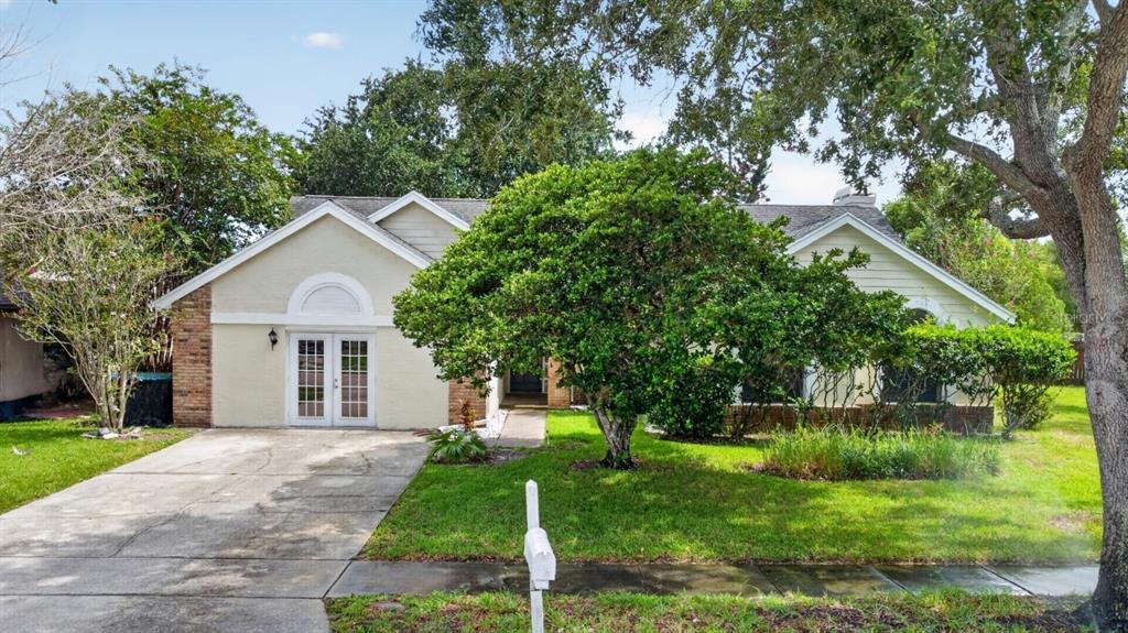A single-story house with a beige exterior, a concrete driveway, and a large front tree — 2024 NORFIELD COURT, ORLANDO, FL