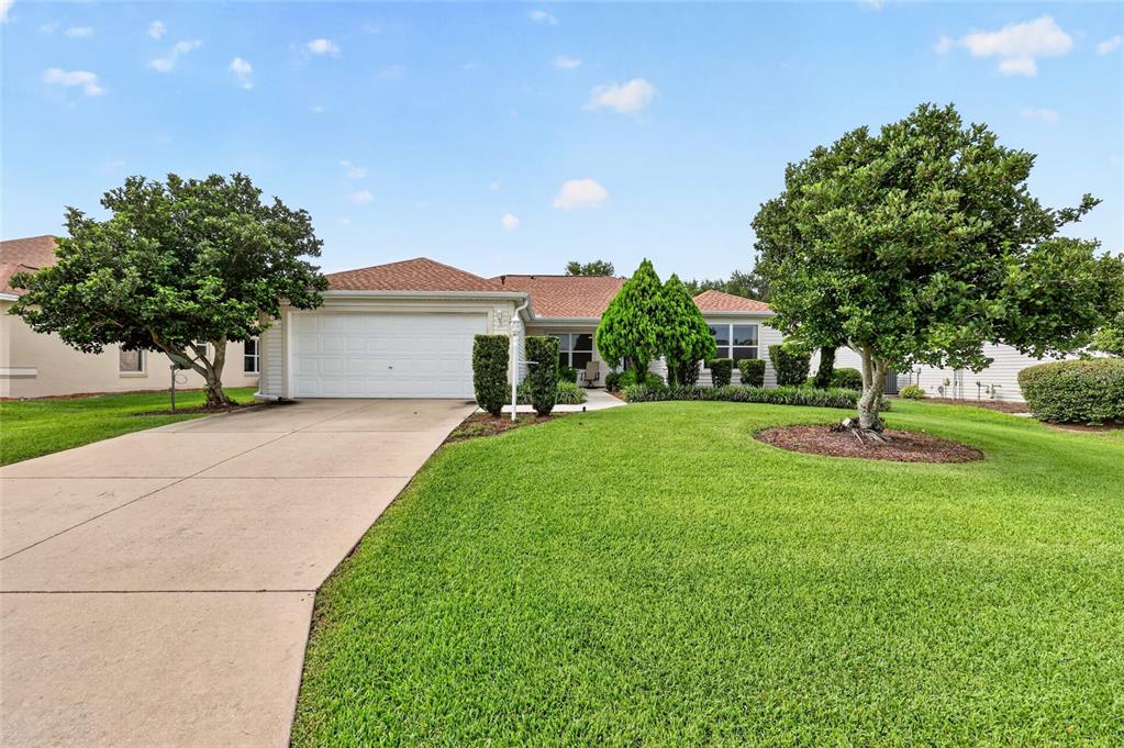 A single-story house with a white garage, a concrete driveway, and a large green lawn — 168 PALERMO PLACE, LADY LAKE, FL