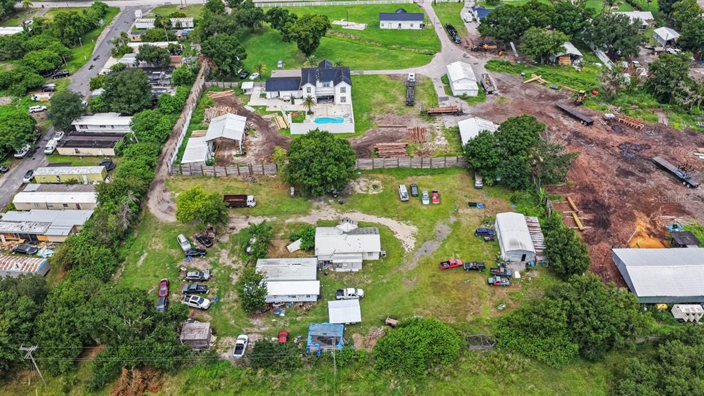 An aerial view shows a rural property with multiple buildings, outbuildings, and several parked vehicles — 5610 CAJUN ROOSTER TRAIL, WIMAUMA, FL
