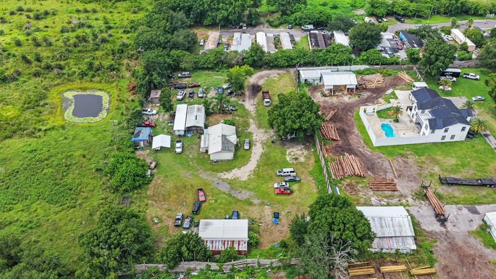 An aerial view shows a rural property with multiple buildings, vehicles, and a swimming pool — 5610 CAJUN ROOSTER TRAIL, WIMAUMA, FL