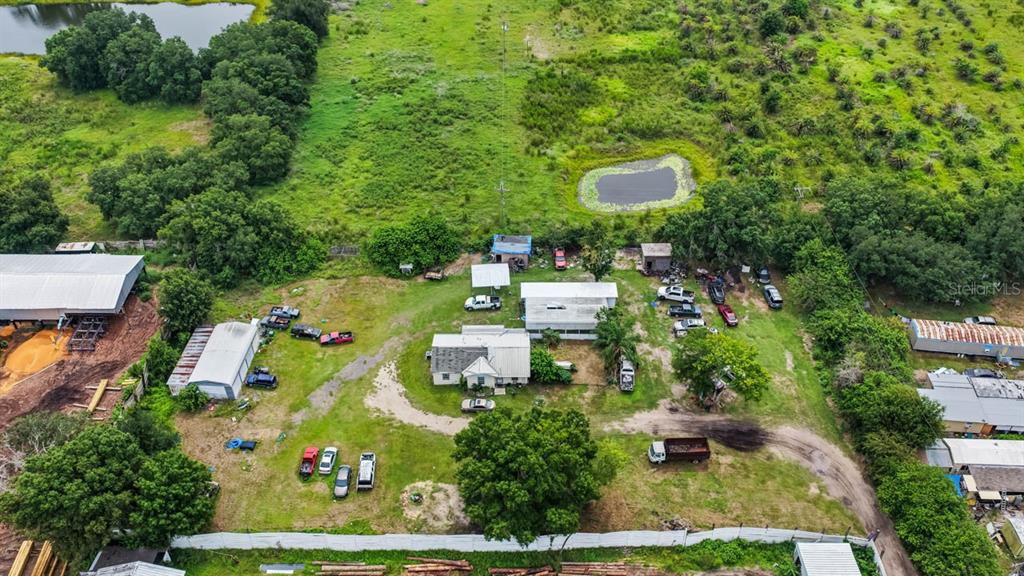 An aerial view shows a rural property with a house, several outbuildings, and multiple vehicles — 5610 CAJUN ROOSTER TRAIL, WIMAUMA, FL