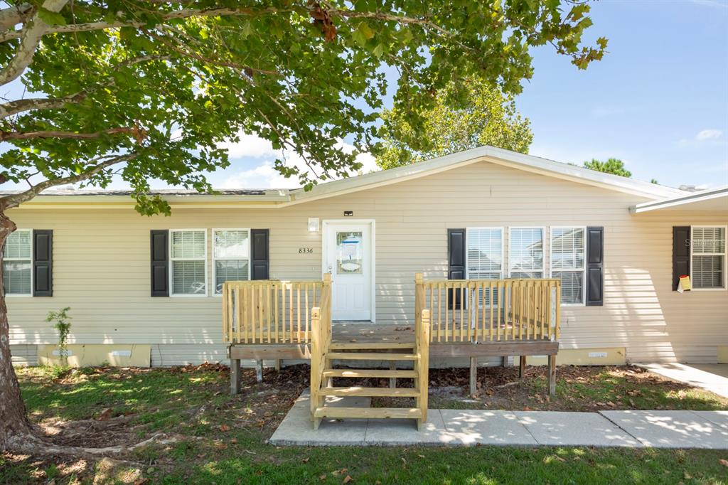 A single-story house with light siding, black shutters, and a wooden front porch with stairs — 8336 CHANCE DRIVE, LAKELAND, FL