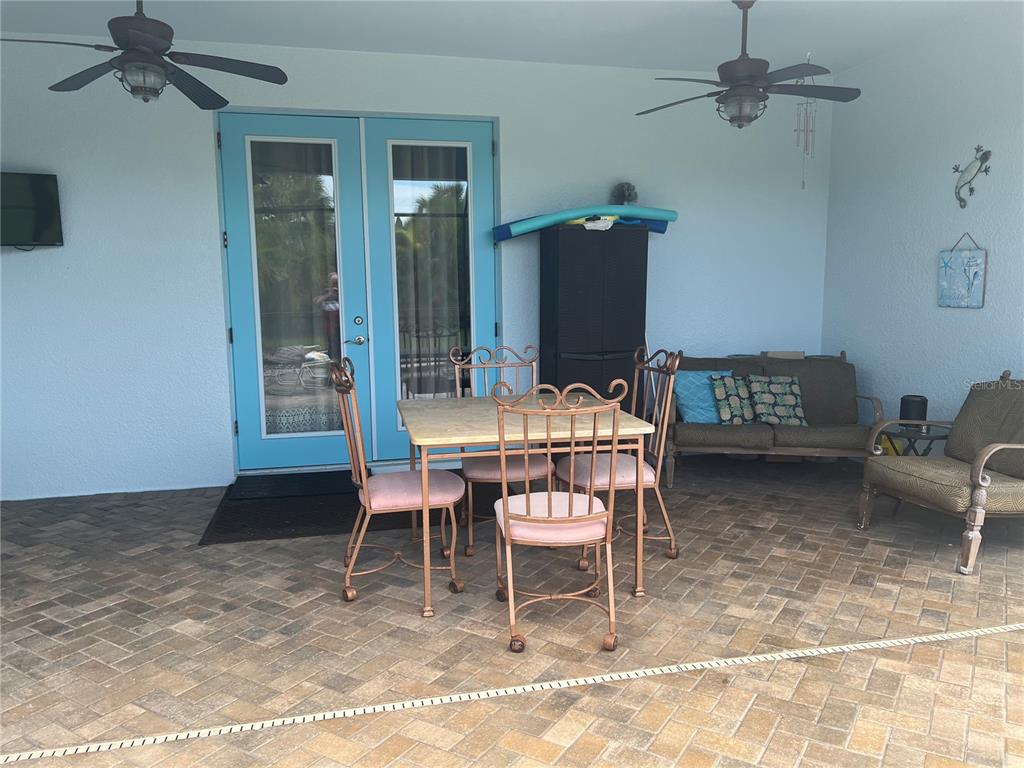 A covered patio features a dining set, a sofa, an armchair, and blue double doors — 11 BROADMOOR LANE, ROTONDA WEST, FL