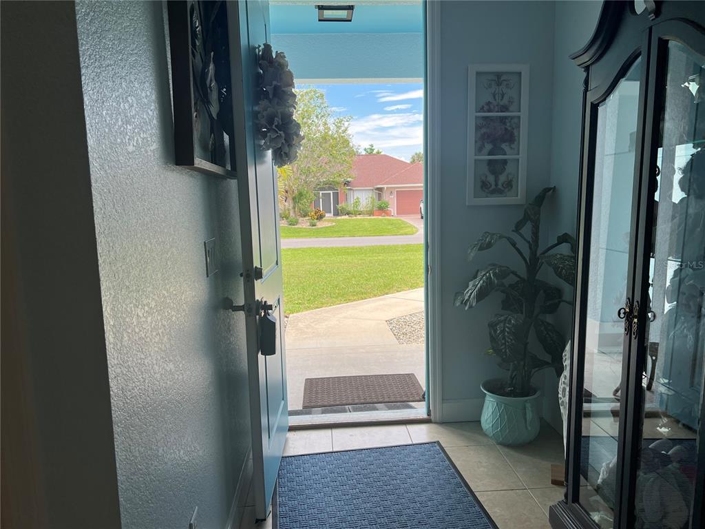 An open front door reveals a view of a suburban street from an indoor entryway — 11 BROADMOOR LANE, ROTONDA WEST, FL