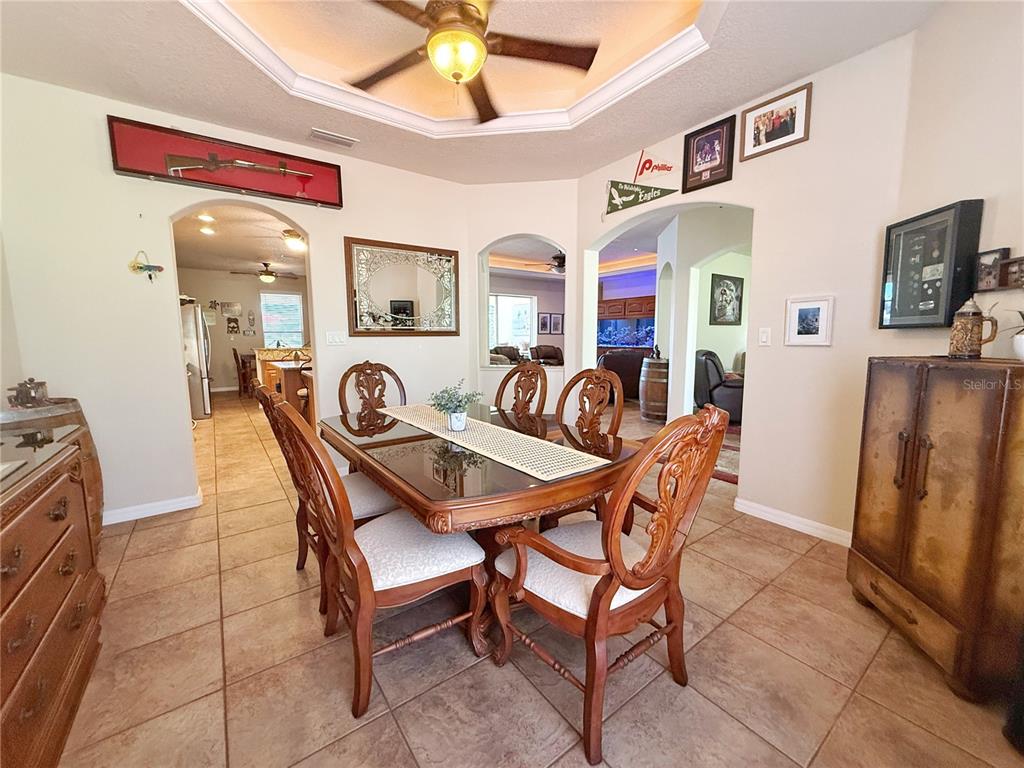 A dining room features a glass-topped table, wooden chairs, tile flooring, and a tray ceiling — 11416 LAKE KATHERINE CIRCLE, CLERMONT, FL
