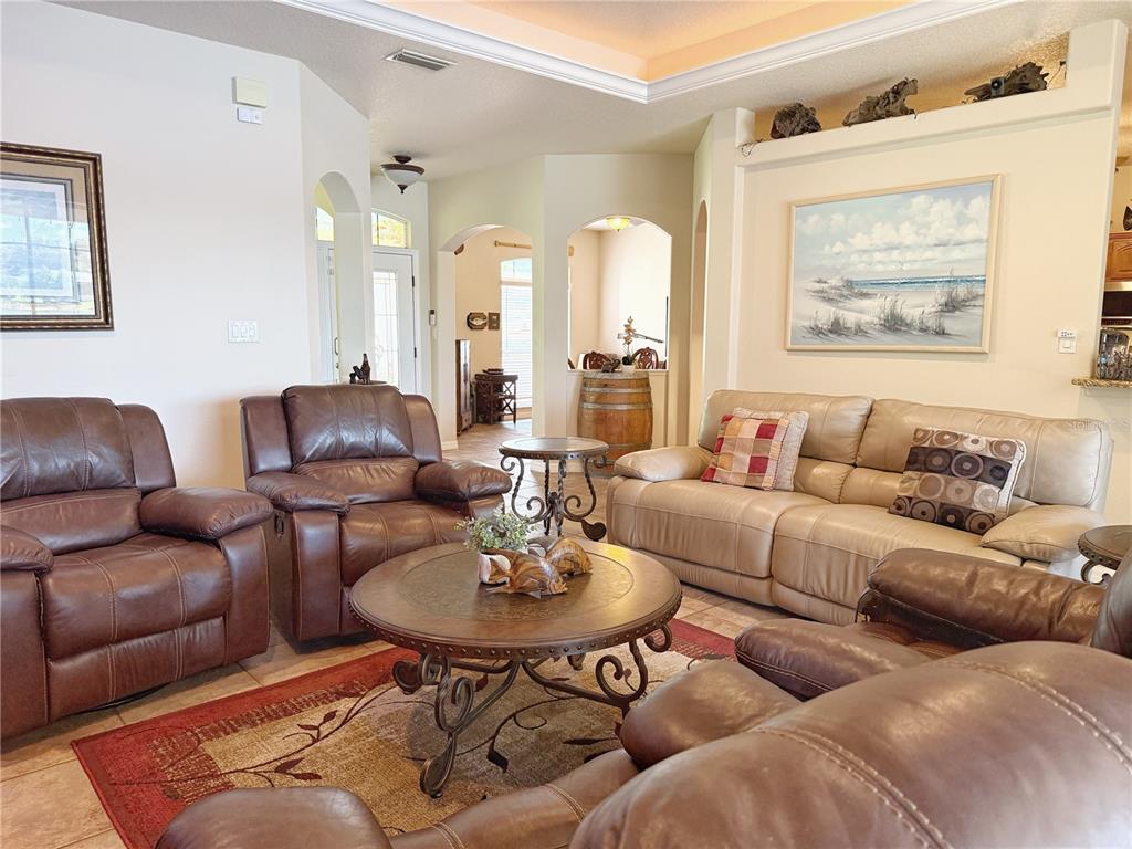 A living room features brown leather recliners, a beige sofa, and a round wooden coffee table — 11416 LAKE KATHERINE CIRCLE, CLERMONT, FL