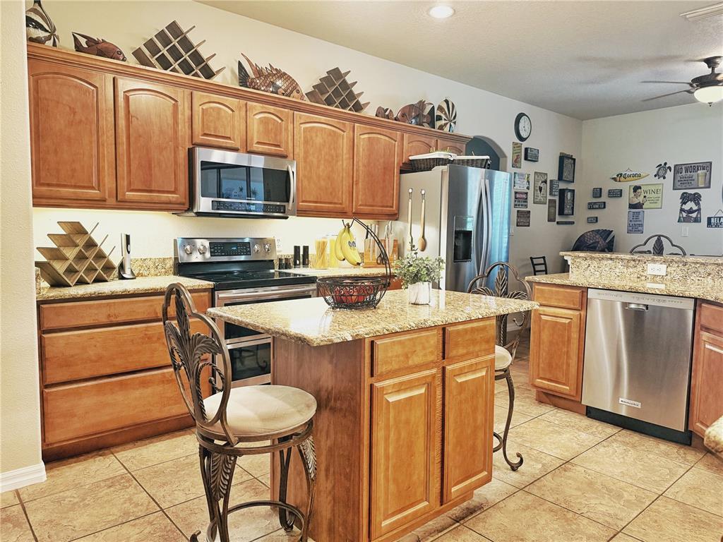 A kitchen features wood cabinets, granite countertops, stainless steel appliances, and a central island — 11416 LAKE KATHERINE CIRCLE, CLERMONT, FL