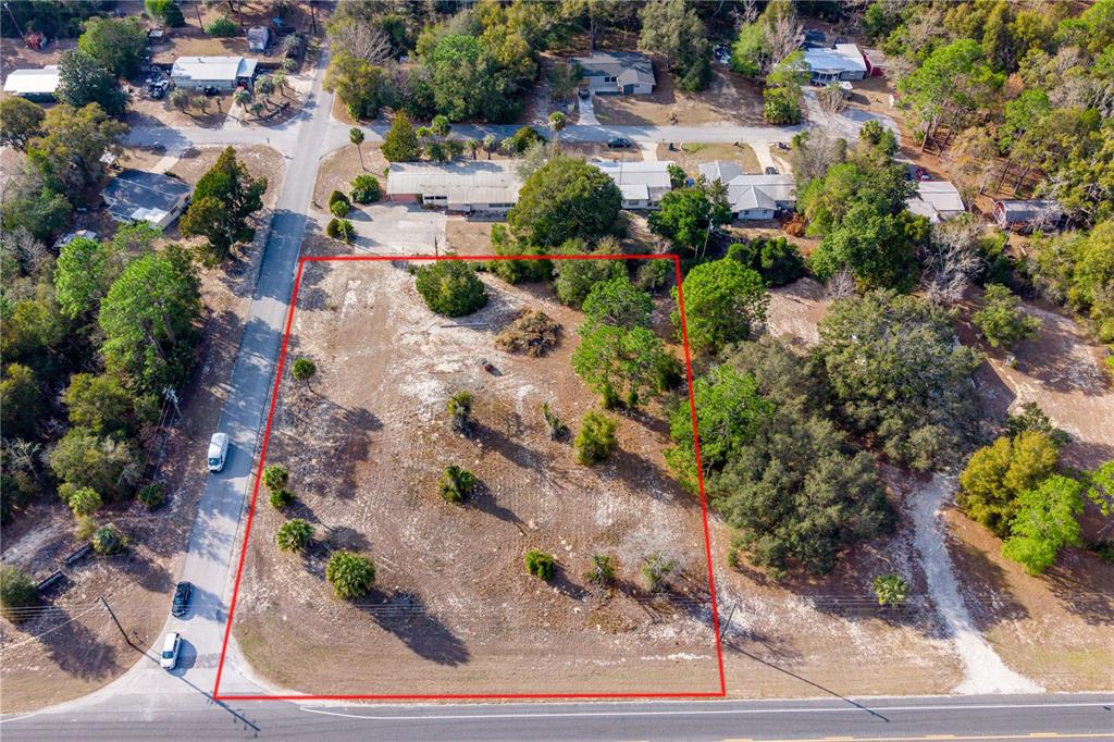 An aerial view shows a vacant, rectangular lot outlined in red next to a paved road — TBD NE STATE RD 121, LOT 2, WILLISTON, FL