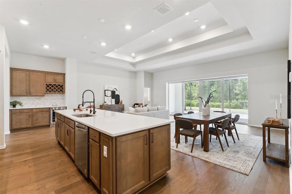 A kitchen with a large island and dining area opens to a bright living space — 15084 CANOPY COVER DRIVE, WINTER GARDEN, FL