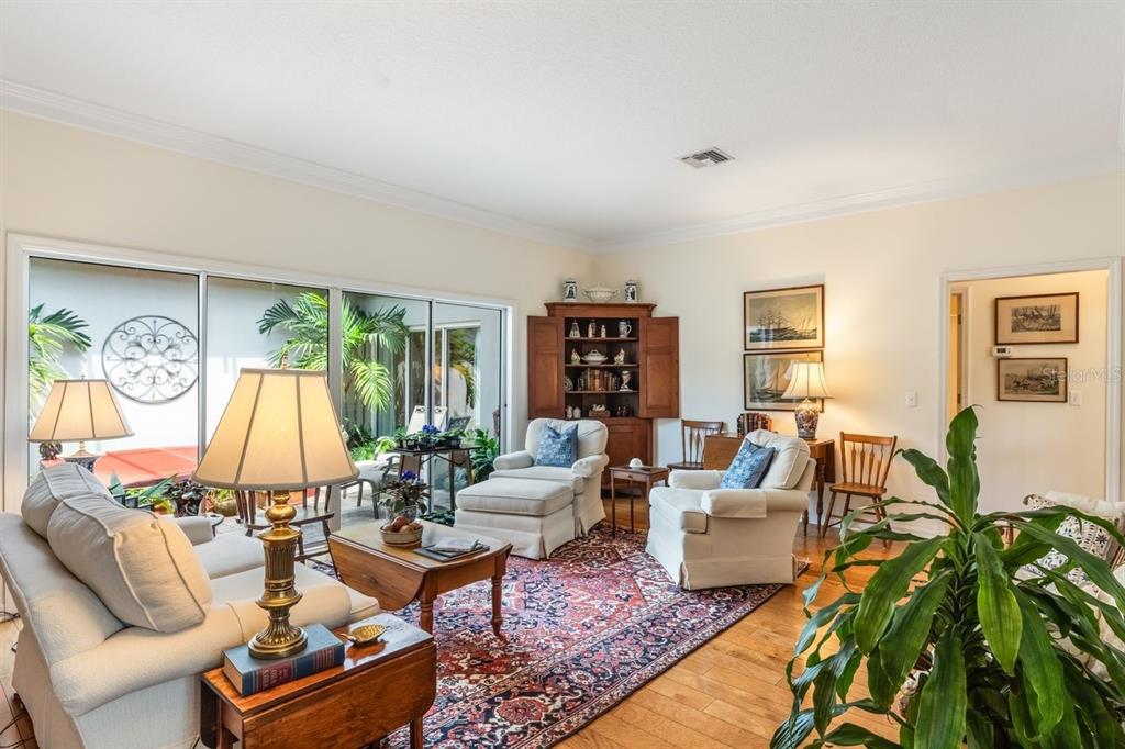 A living room with light walls, hardwood floors, a patterned rug, and sliding glass doors — 2175 S COUNTRYSIDE CIRCLE, ORLANDO, FL