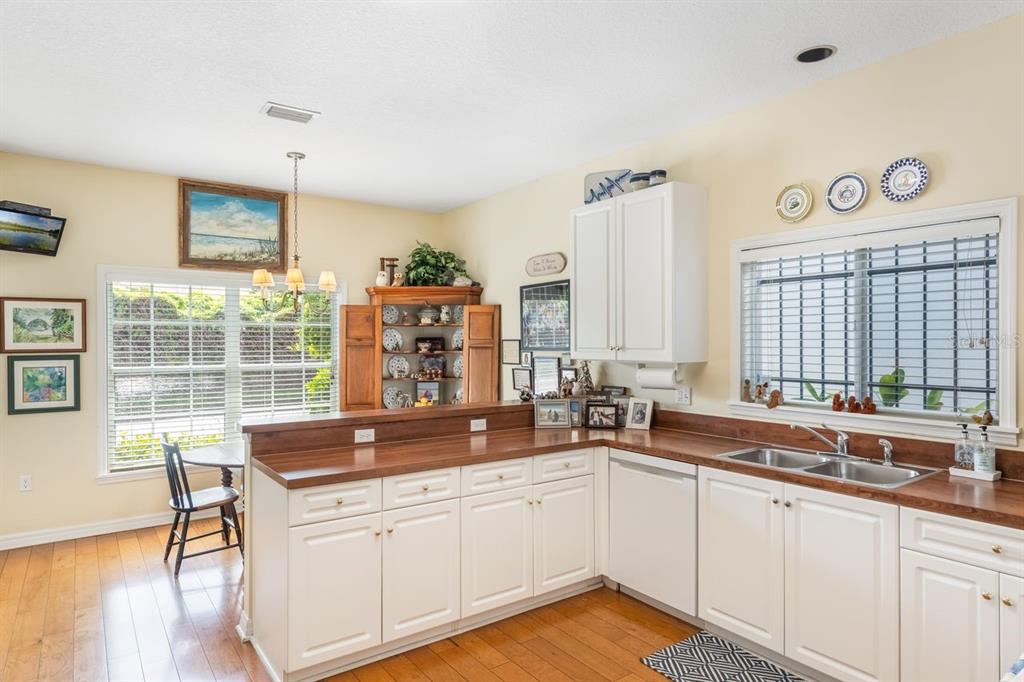 A kitchen features white cabinets, wood countertops, a double sink, and a dining area — 2175 S COUNTRYSIDE CIRCLE, ORLANDO, FL