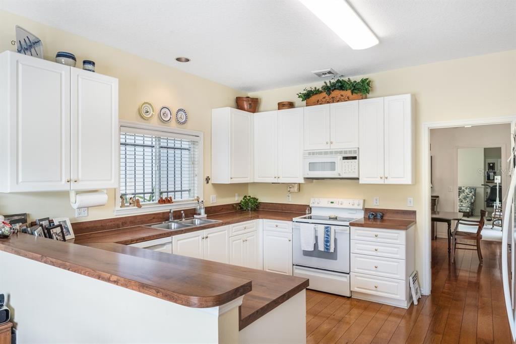 A kitchen features white cabinets, wood countertops, a white stove, and light-colored walls — 2175 S COUNTRYSIDE CIRCLE, ORLANDO, FL