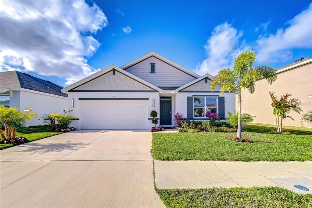 A single-story suburban house with a white garage, gray siding, and a palm tree — 2763 WIDEWATER WAY, ZEPHYRHILLS, FL