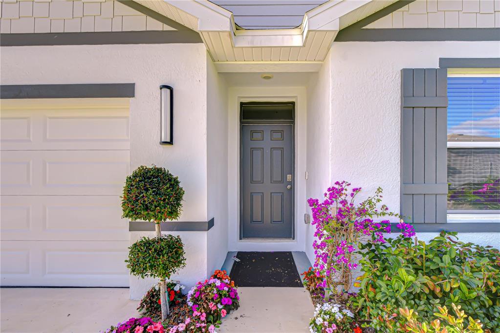 A front exterior view of a house featuring a gray door, garage, and landscaping — 2763 WIDEWATER WAY, ZEPHYRHILLS, FL