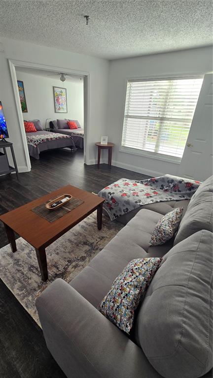 A living room with a gray sofa and coffee table opens into a bedroom beyond — 3100 PARKWAY BOULEVARD UNIT 123, KISSIMMEE, FL