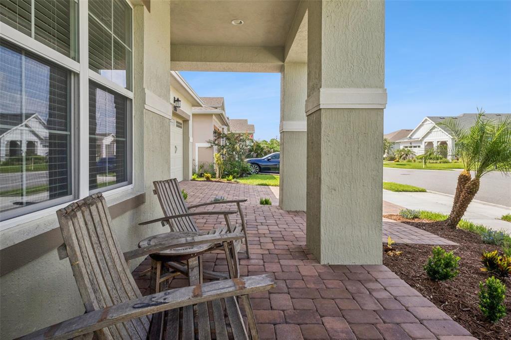A covered front porch features brick pavers, two wooden chairs, and a small side table — 5087 TWIN LAKES BOULEVARD, ST CLOUD, FL