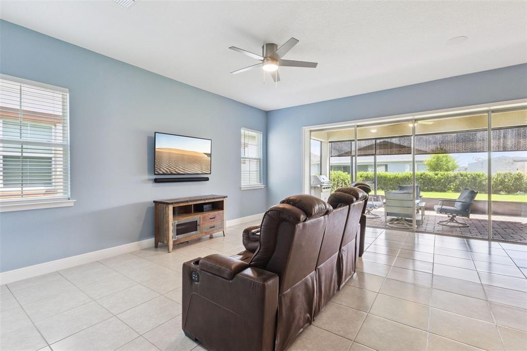 A living room features light blue walls, tile flooring, a brown leather sofa, and sliding doors — 5087 TWIN LAKES BOULEVARD, ST CLOUD, FL