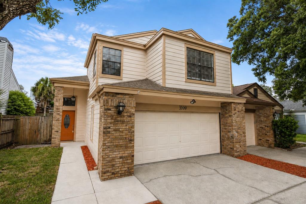 A two-story house with a brick and beige siding exterior, two garages, and a driveway — 3109 BRIDGEFORD DRIVE, ORLANDO, FL