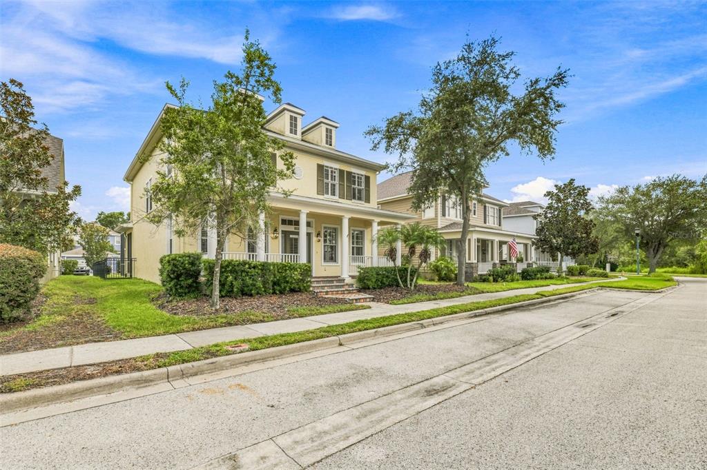 A yellow two-story house with a front porch and dormer windows sits along a street — 6104 PARKSET DRIVE, LITHIA, FL