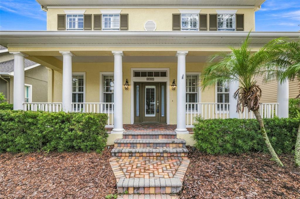 A yellow two-story house with a front porch, white columns, and a brick walkway — 6104 PARKSET DRIVE, LITHIA, FL