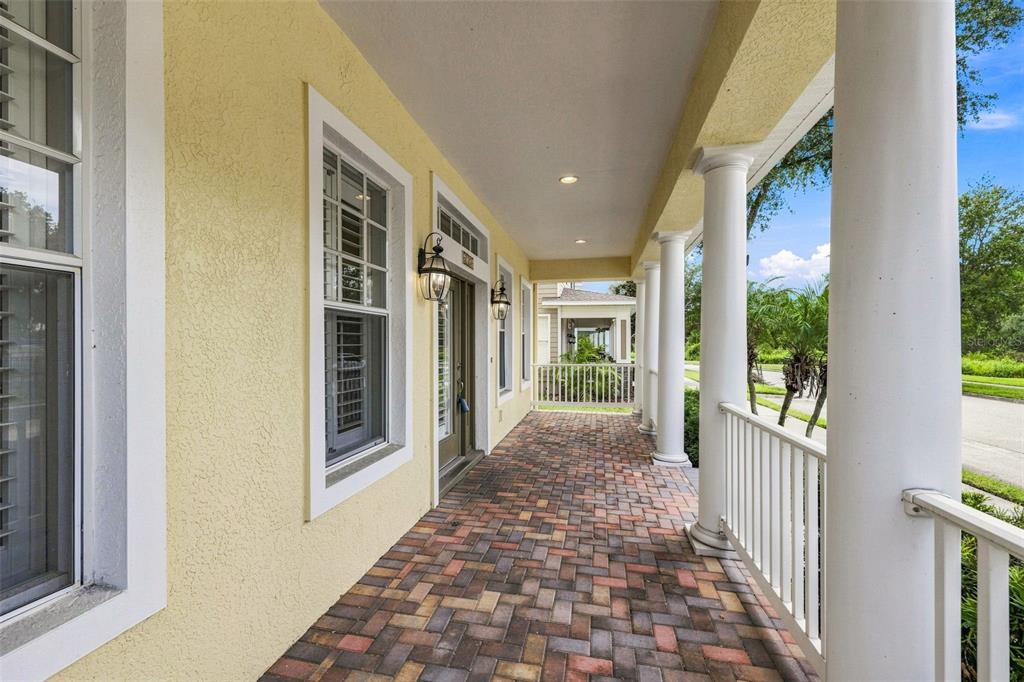 A covered porch features yellow stucco walls, white columns, and a herringbone-patterned brick floor — 6104 PARKSET DRIVE, LITHIA, FL