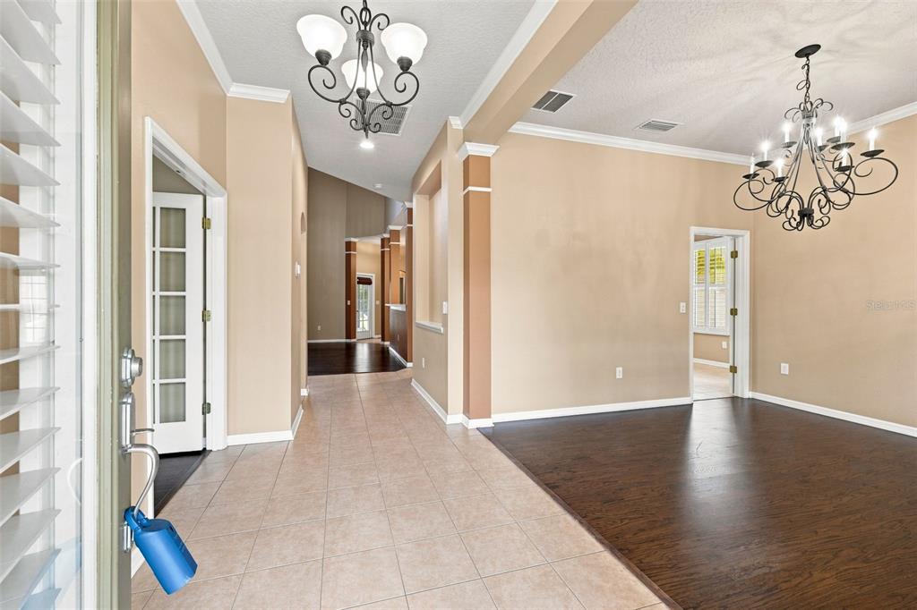 An entryway with tile flooring leads to a dining room with dark wood floors and chandeliers — 6104 PARKSET DRIVE, LITHIA, FL