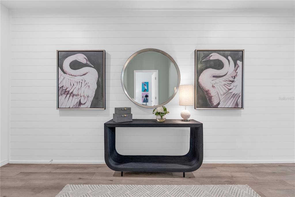 A console table sits against a white shiplap wall beneath a round mirror and artwork — 2230 LINK LOOP, ST CLOUD, FL