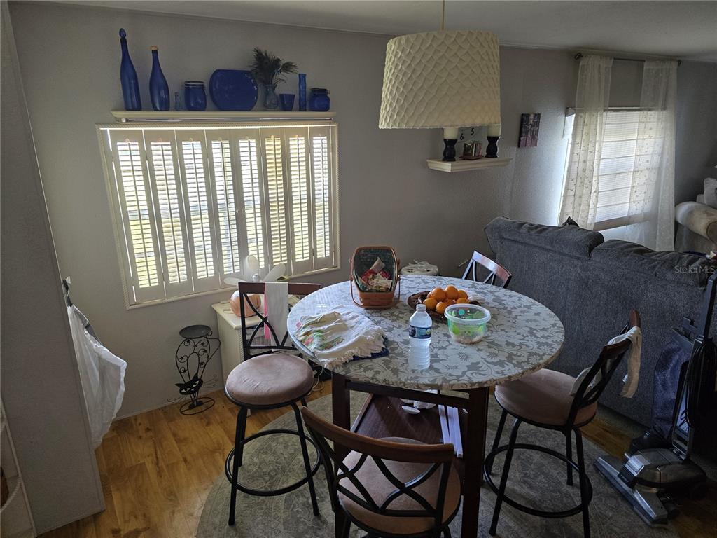 A dining area features a round table, four chairs, a window with shutters, and blue decor — 5316 53RD AVENUE E UNIT F21, BRADENTON, FL
