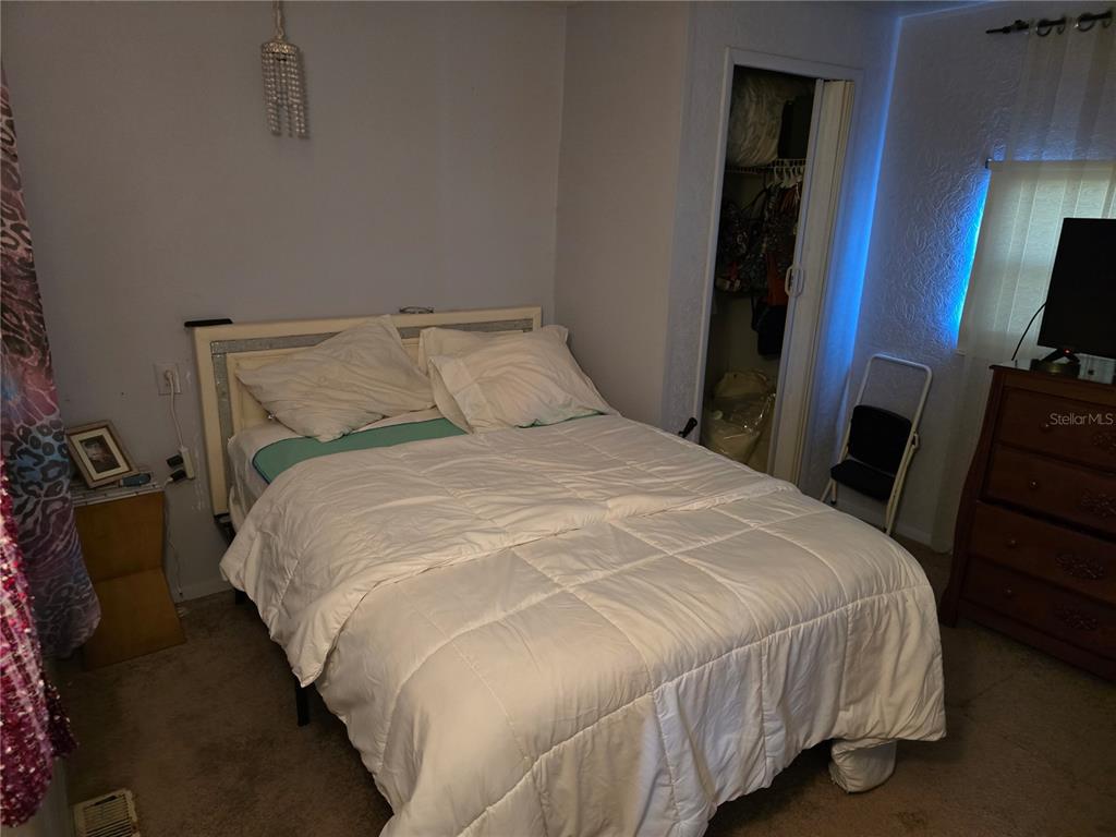 A bedroom features a white bed, a wooden dresser, and a closet with folding doors — 5316 53RD AVENUE E UNIT F21, BRADENTON, FL