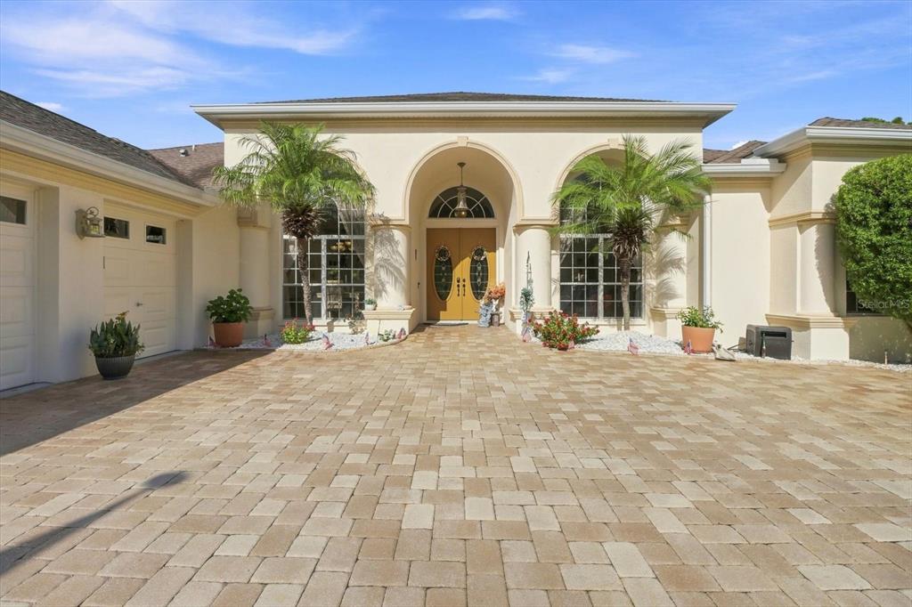 The exterior of a beige house features a paved driveway, arched entryway, and two palm trees — 564 N AFTERGLOW CIRCLE, CRYSTAL RIVER, FL