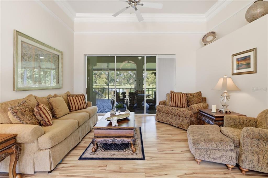 A living room with a beige sofa, patterned armchair, wood coffee table, and sliding glass doors — 564 N AFTERGLOW CIRCLE, CRYSTAL RIVER, FL