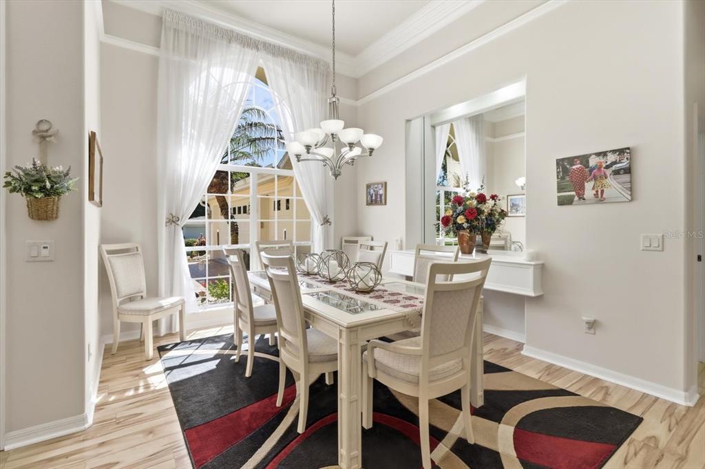 A dining room features a white table, six chairs, a chandelier, and a large arched window — 564 N AFTERGLOW CIRCLE, CRYSTAL RIVER, FL