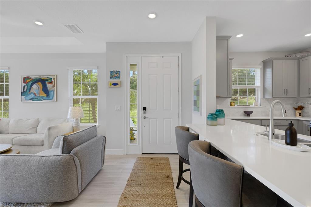 A living room and kitchen area feature light gray walls, white cabinets, and a white island — 4773 TORTONA COURT, BRADENTON, FL