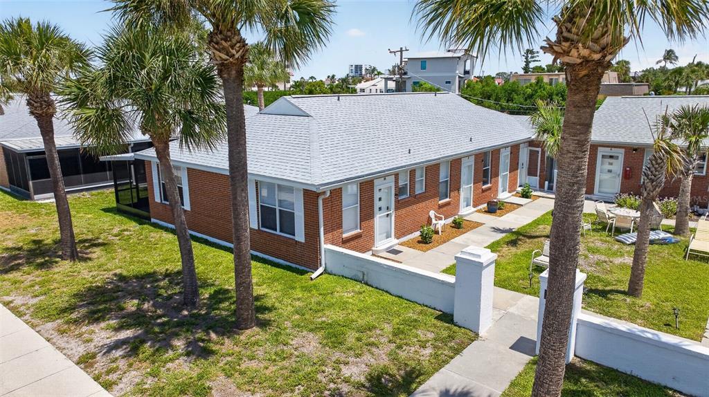 An exterior view of a single-story brick apartment building with palm trees and a lawn — 908 VILLAS DRIVE UNIT 10, VENICE, FL
