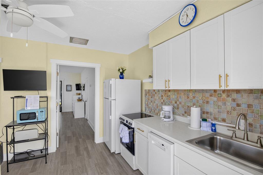 A kitchen features white cabinets, a tiled backsplash, stainless steel sink, and light flooring — 908 VILLAS DRIVE UNIT 10, VENICE, FL