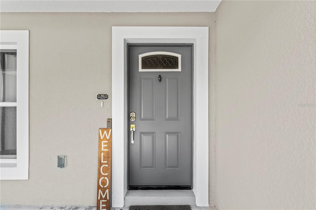 A gray front door with a small window and a vertical welcome sign sits outside — 18 DOGWOOD TRAIL COURSE, OCALA, FL