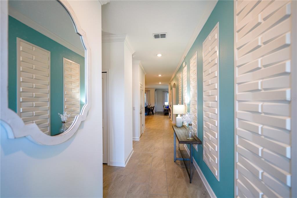 A hallway with teal walls, white decorative panels, a mirror, and a console table — 3020 PROTAGONIST STREET, KISSIMMEE, FL