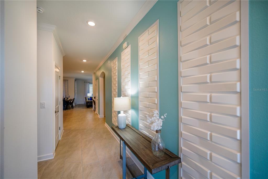 A hallway features teal walls with white decorative panels, a wooden console table, and tile flooring — 3020 PROTAGONIST STREET, KISSIMMEE, FL