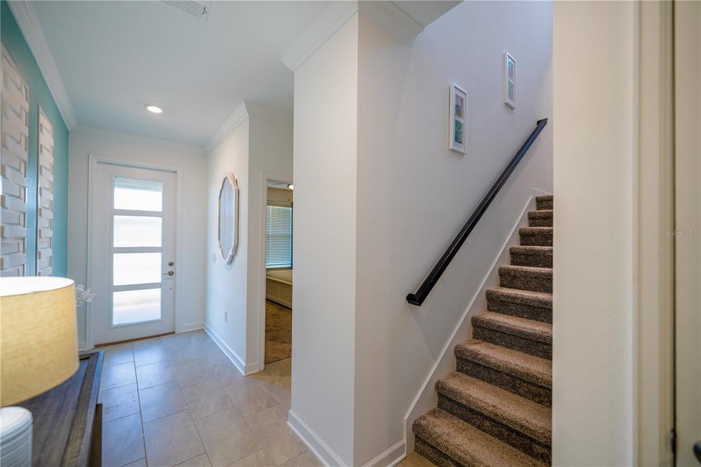 An entryway features tile flooring, a front door with glass panels, and carpeted stairs — 3020 PROTAGONIST STREET, KISSIMMEE, FL